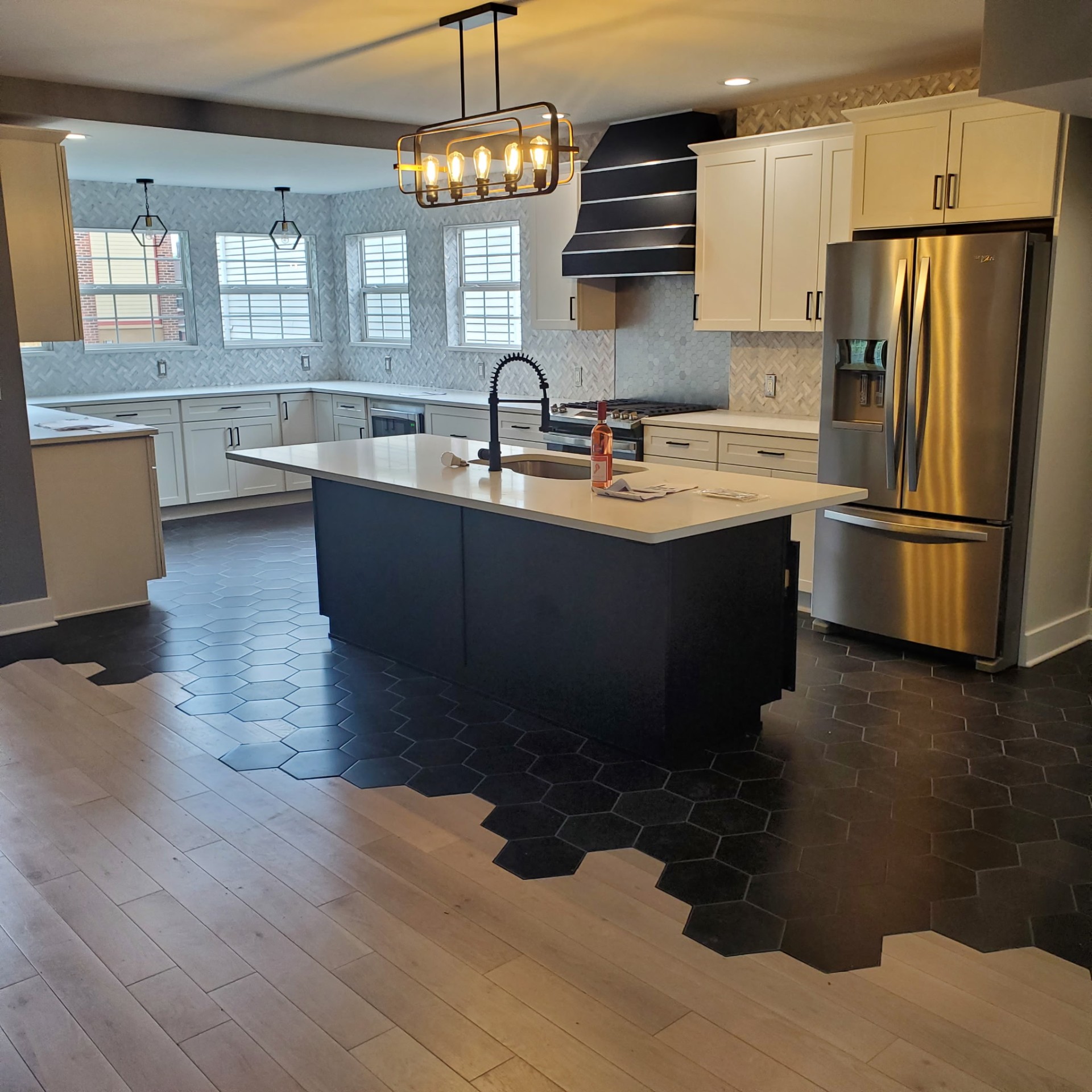 Open-concept chef's kitchen with custom hood, hex tile inlay, and quartz island — Trademark Design